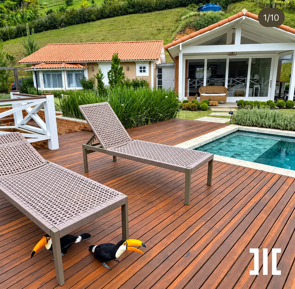 Deck de madeira com espreguiçadeiras e piscina, com dois tucanos pousados no chão